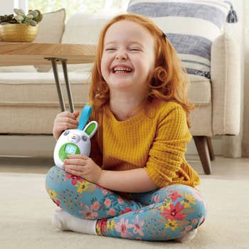 A child holding the bunny-shaped story player and laughing