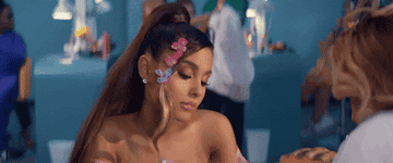 GIF of Ariana looking bored as she inspects her nails