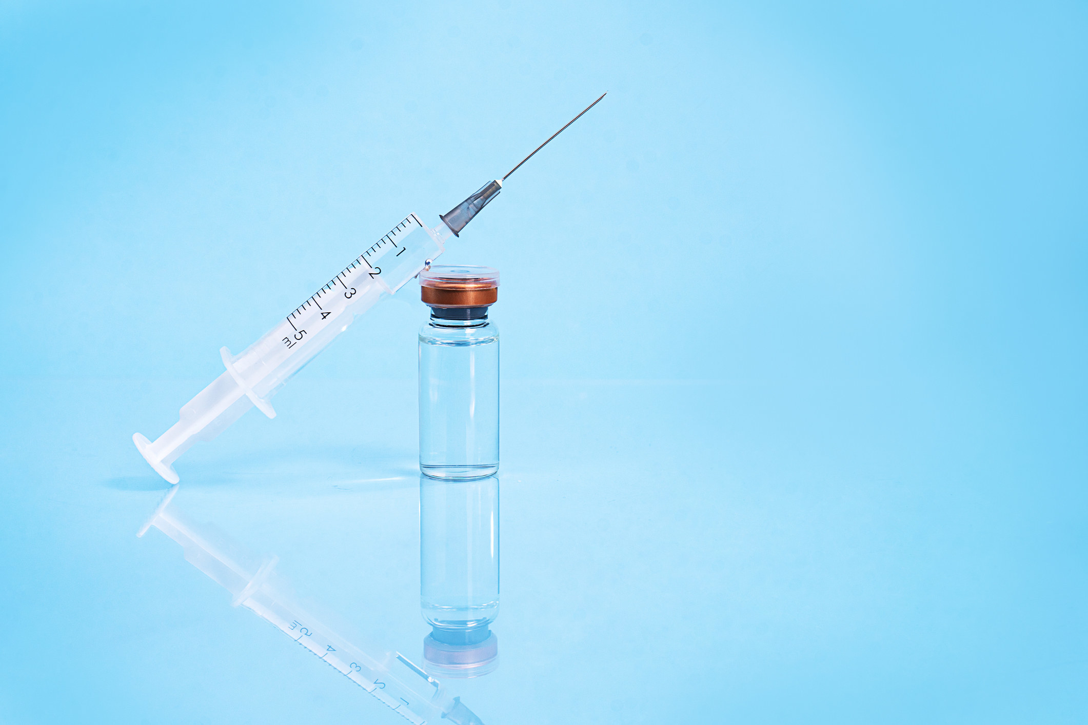 A photo of a needle syringe leaning on a medicine bottle
