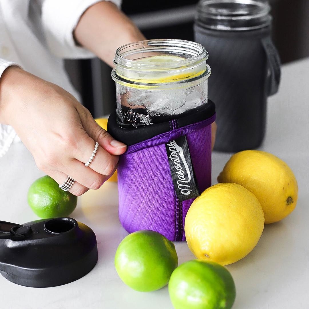A person putting the neoprene sleeve over a Mason jar