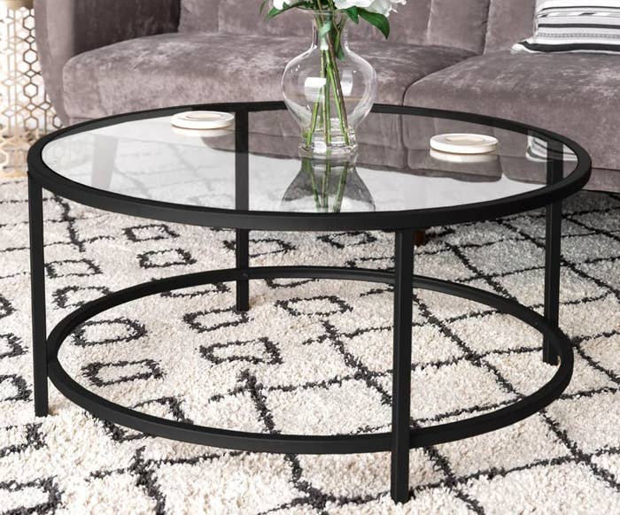 A black/glass, round coffee table in a living room