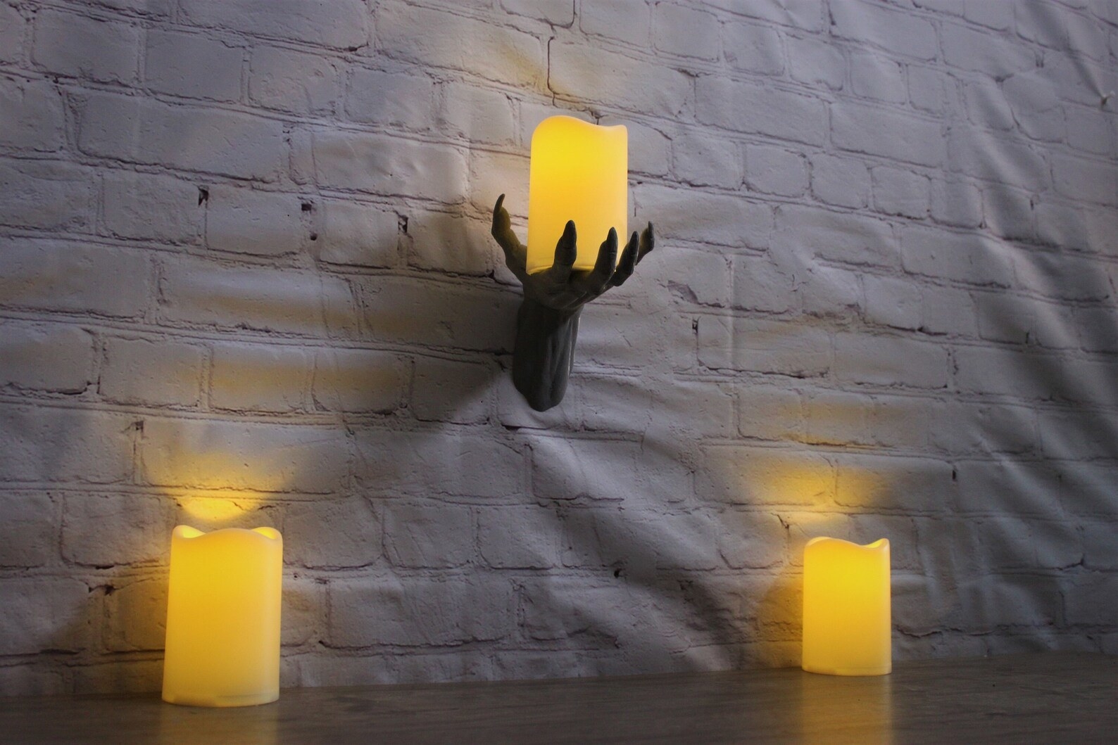 creepy 3D printing hand mounted to the wall holding an LED candle