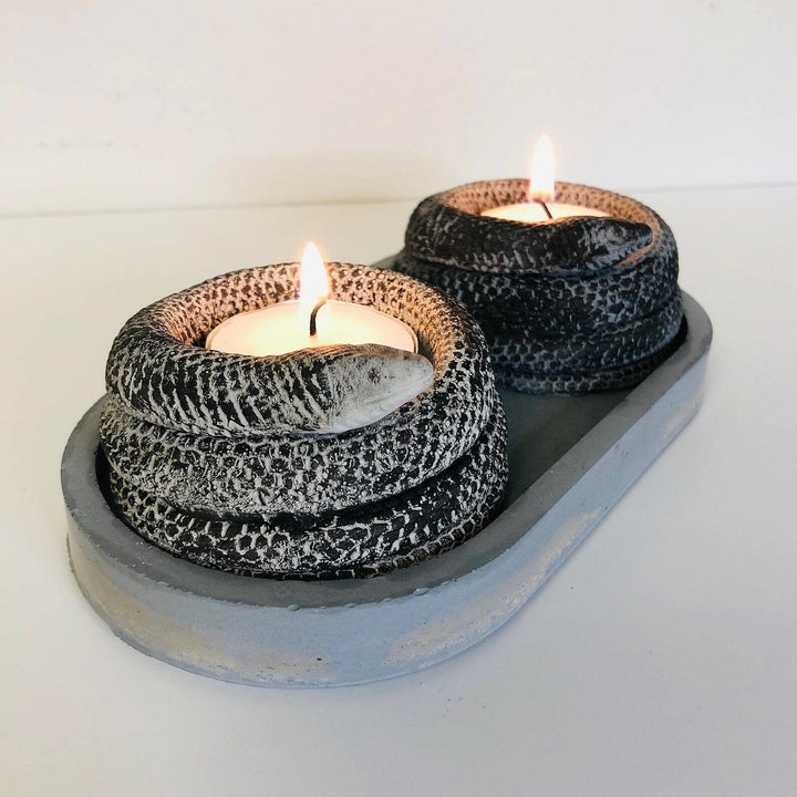 two mini coiled snakes on an oval tray with lit tea candles inside their center