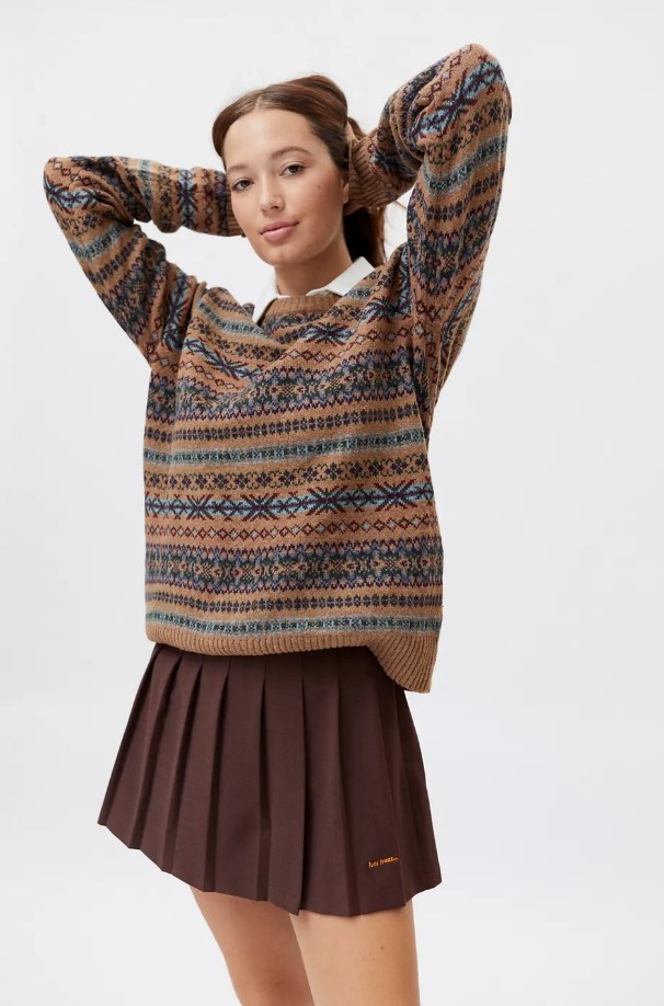 Model wearing pleated brown skirt with patterned sweater