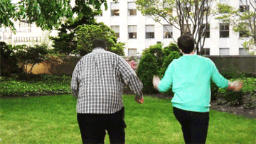 a gif of two people frolicking merrily on the grass