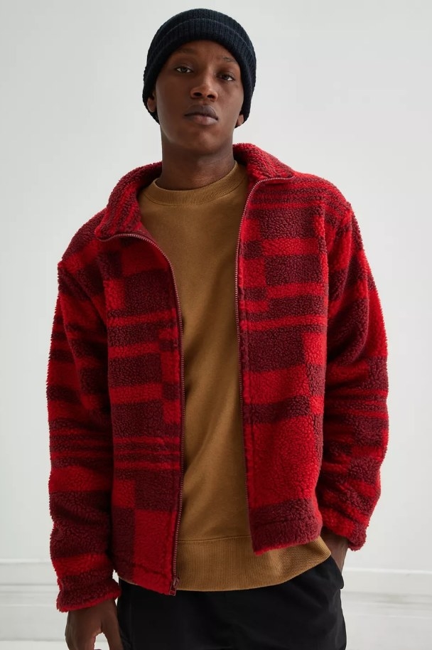Model wearing red plaid sherpa jacket with tan shirt underneath