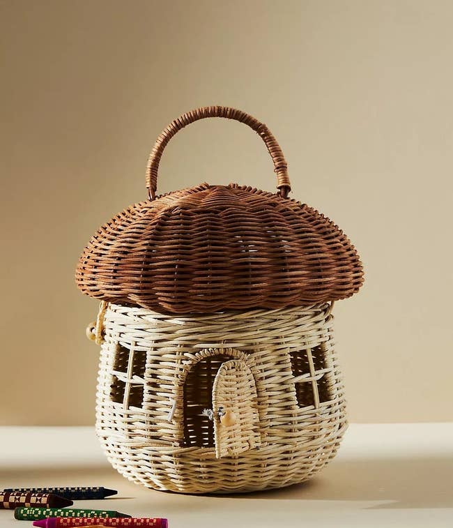 wicker basket in the shape of a mushroom, with a hinged front door and windows on the front