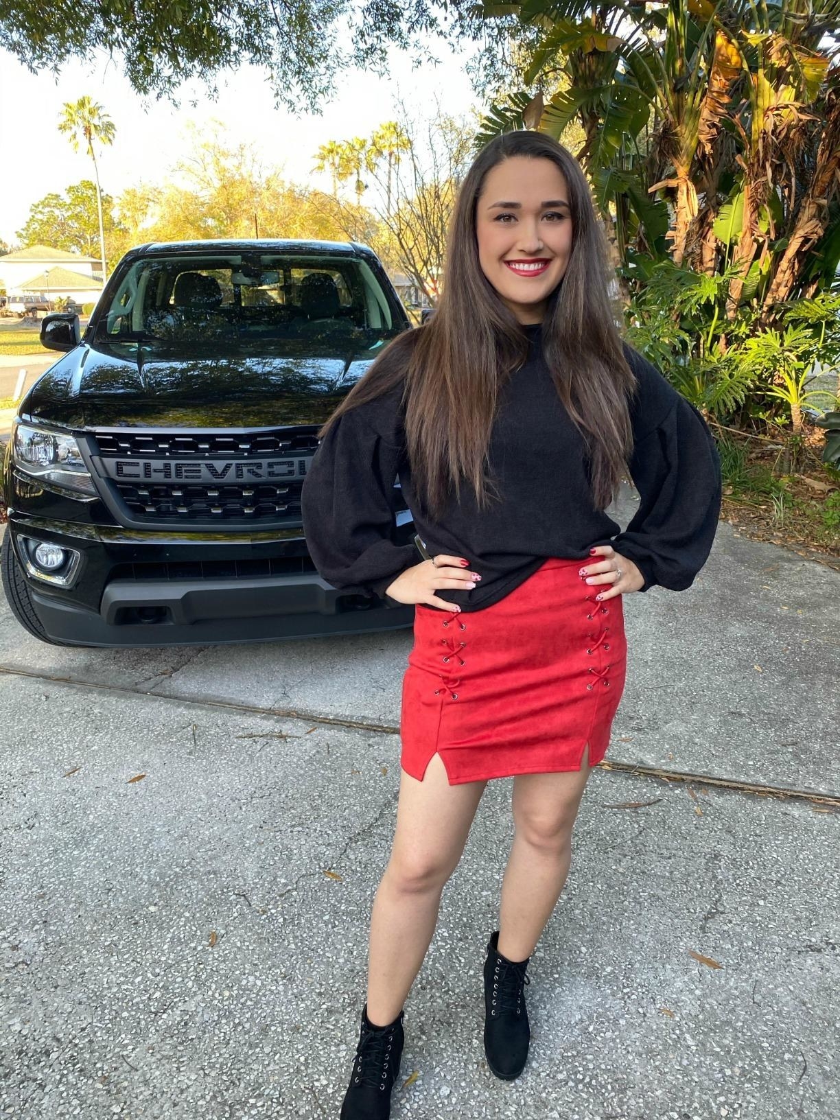 Reviewer is wearing the black lantern sleeve pullover sweater with a red mini skirt and black boots