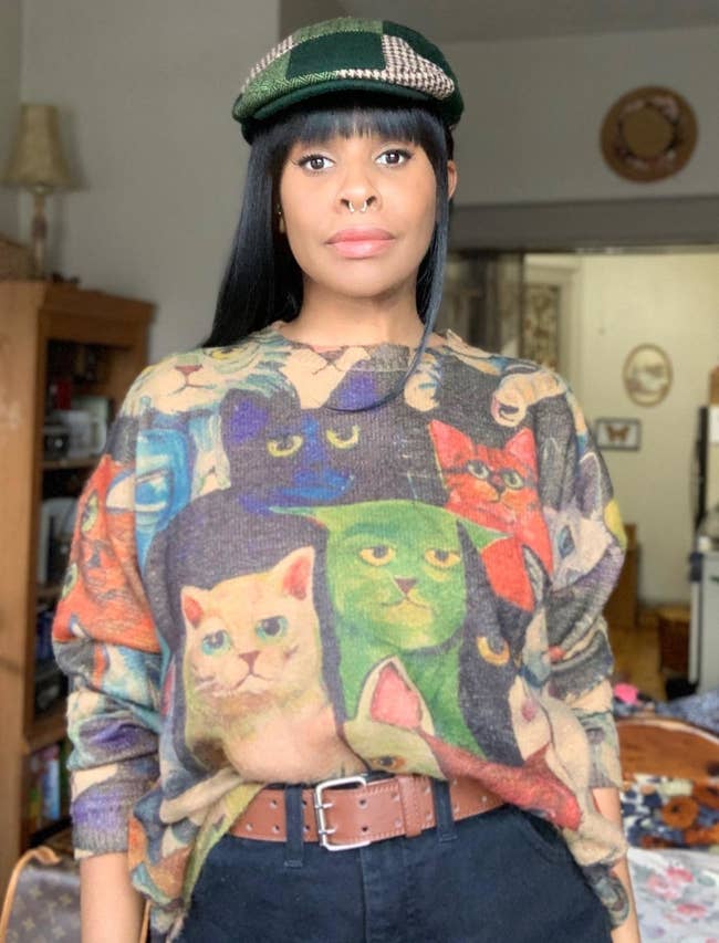 Reviewer is wearing the graphic sweater with grumpy looking cats printed all over it