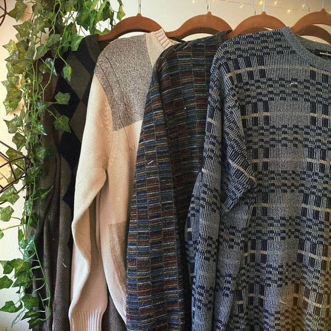 Four vintage sweaters hanging on a rack