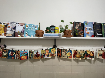 kitchen shelf with cook books on top and halloween cards hanging from twine below