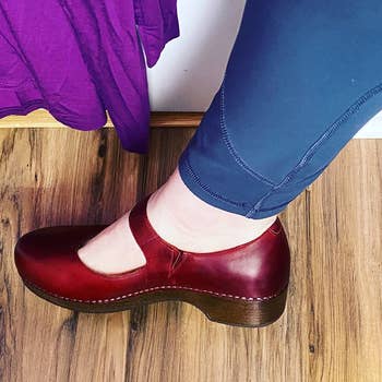 a profile view of a reviewer wearing the clogs in burgundy