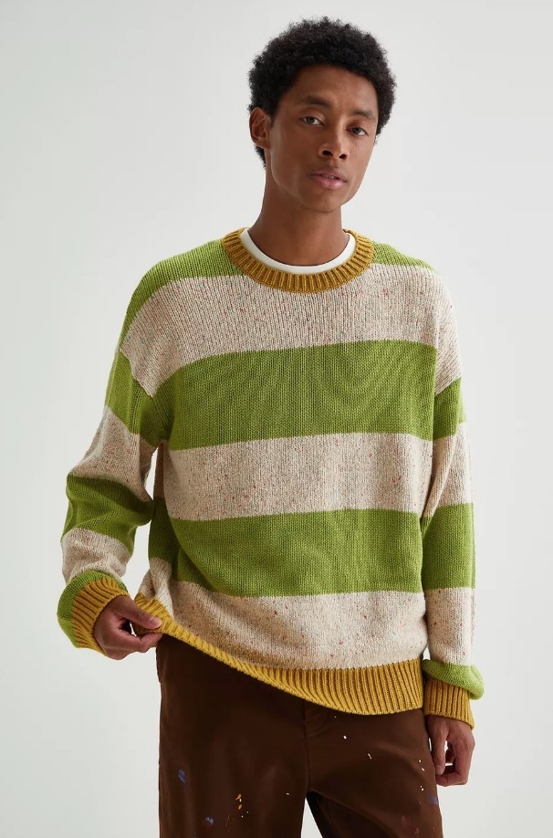 a model wearing a green and off-white striped knit sweater and brown pants