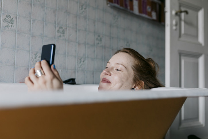 woman on phone while in bathtub