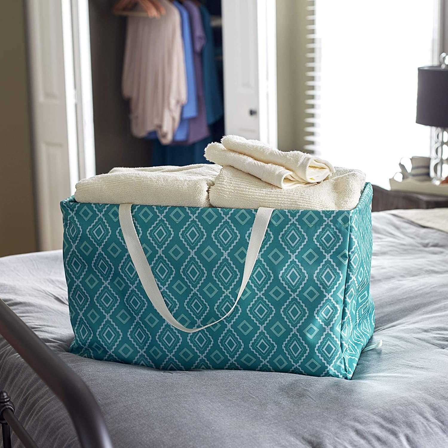 The utility tote with towels inside on a bed