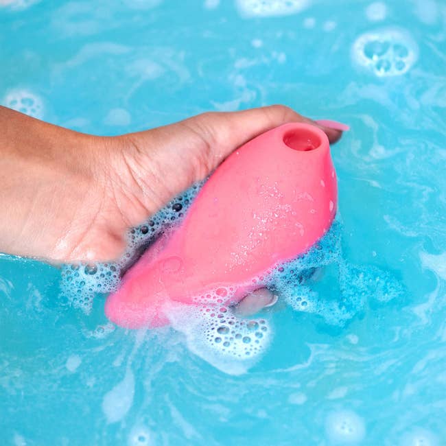 Model holding pink suction vibrator in soapy water