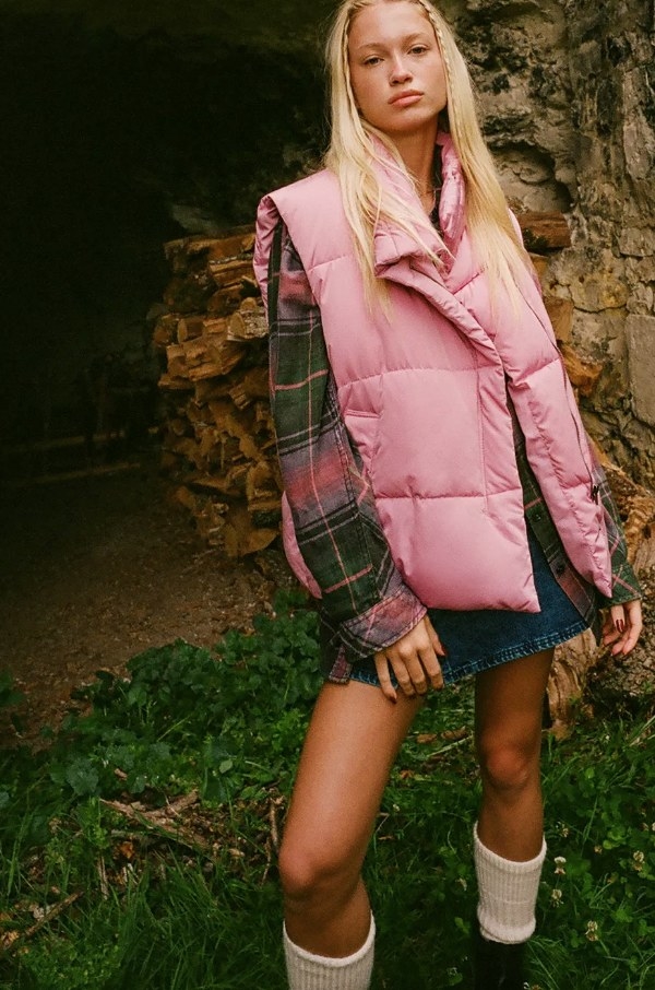 Model wearing pink puffer vest with flannel and denim skirt