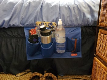 blue bedside caddy with water bottles, thermos, remotes, tucked into mattress