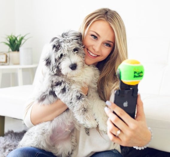 Model with dog holding pooch selfie stick.