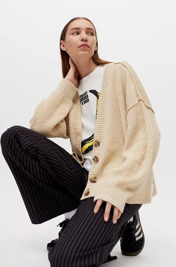 Model wearing beige cardigan with white band tee and black pants