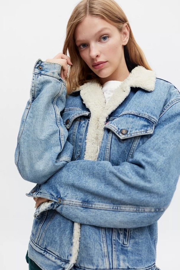 Model wearing a denim jacket with white sherpa collar and lining
