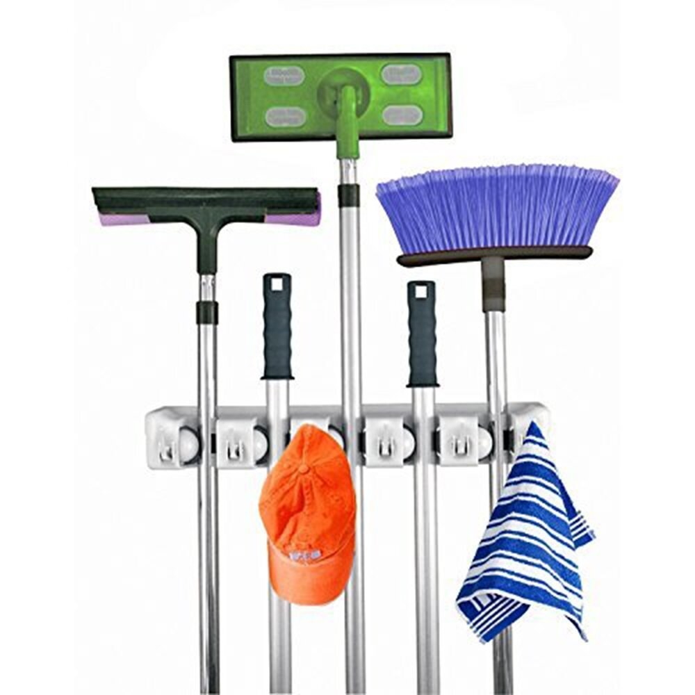 the holder with five long-handled mops/brooms in it, and two items hung on the five hooks