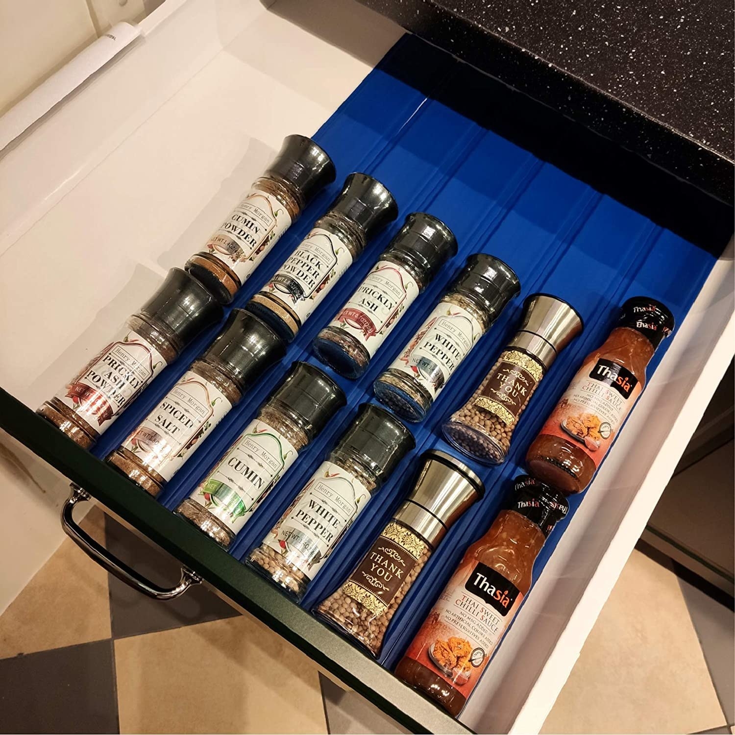 A drawer lined with strips of drawer liner, there are spices on top