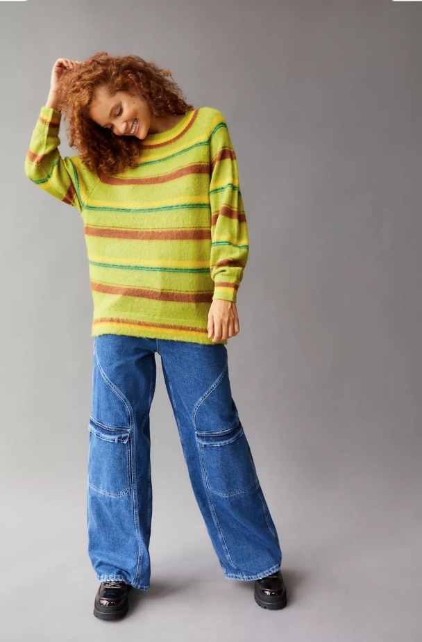 Model wearing green, orange and yellow striped pullover sweater with jeans