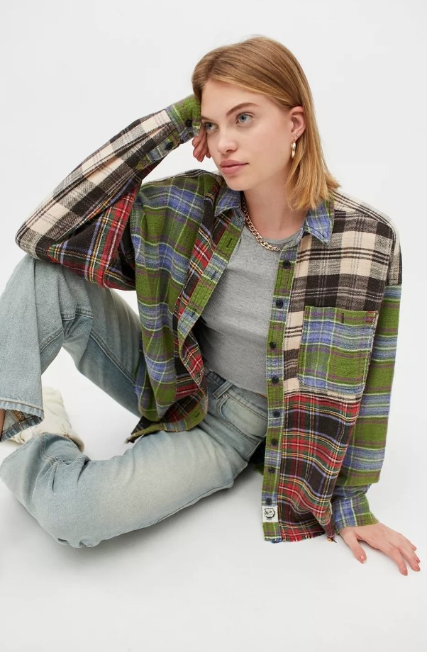 Model wearing multicolored plaid flannel with gray top and jeans