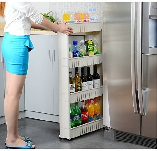 A woman wheeling in a shelf tray with sodas in it in the middle of a fridge and a cabinet
