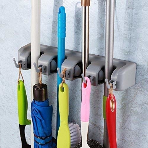 A wall-mounted organiser with brushes and mops on it