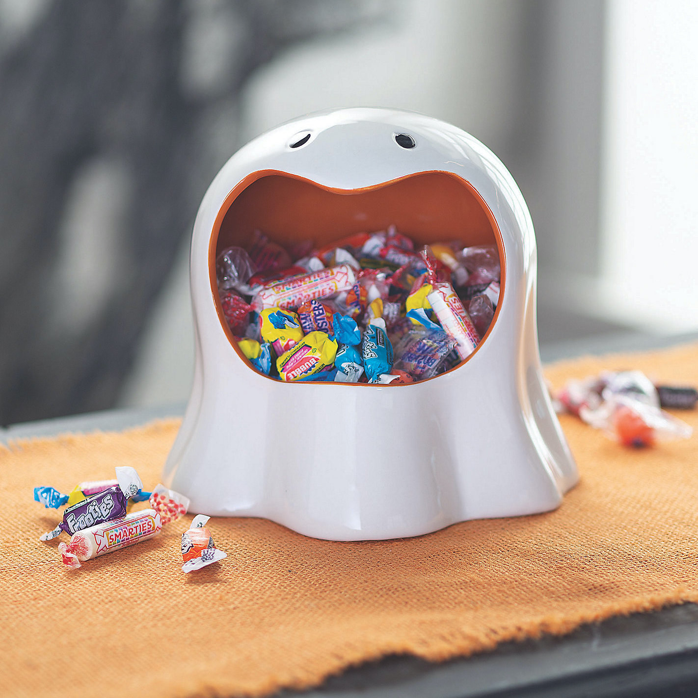 A candy dish in the shape of a ghost holds candy in its mouth