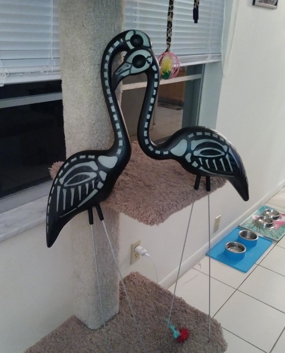 Reviewer&#x27;s two flamingos rest against a cat scratcher