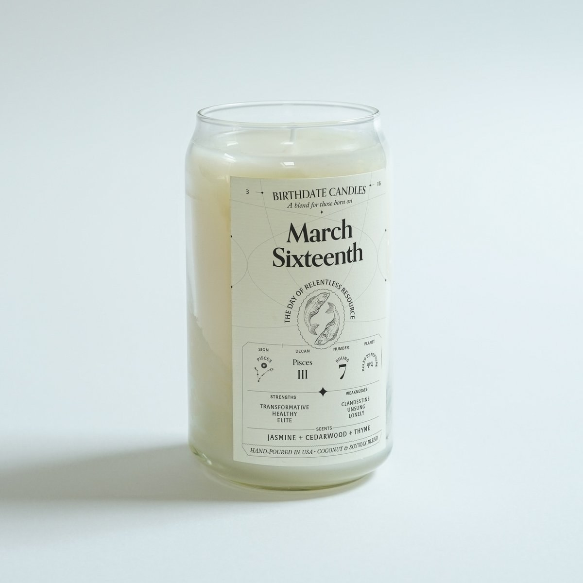 A hand-poured white candle in a jar with a label that says 