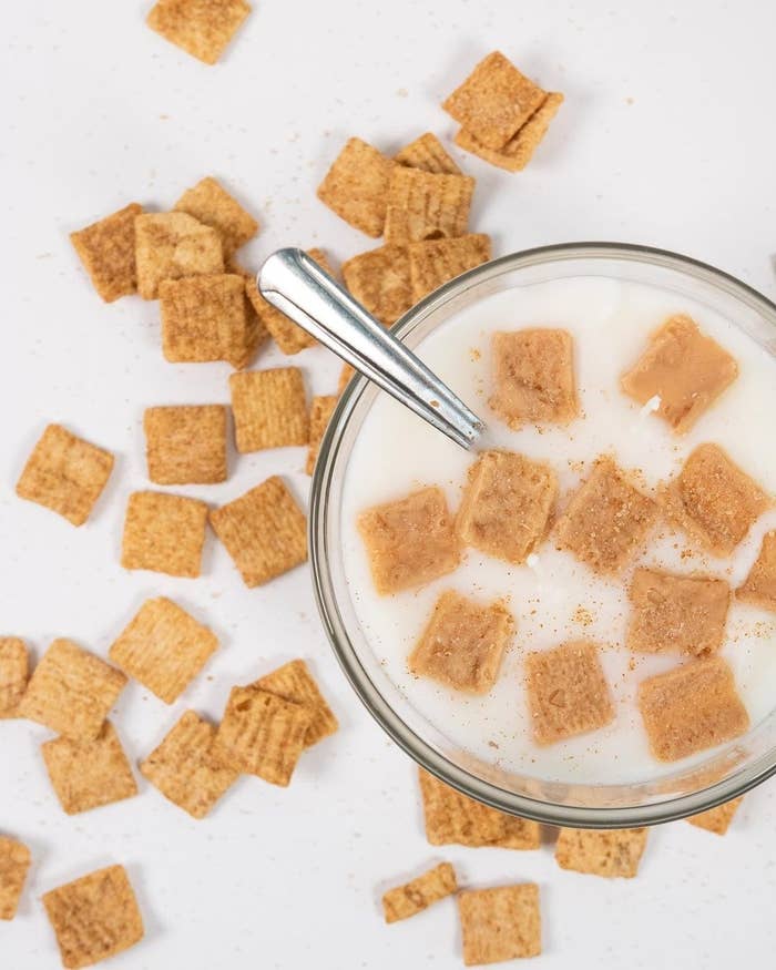 A glass bowl with white soy wax inside and little cinnamon toast squares on top