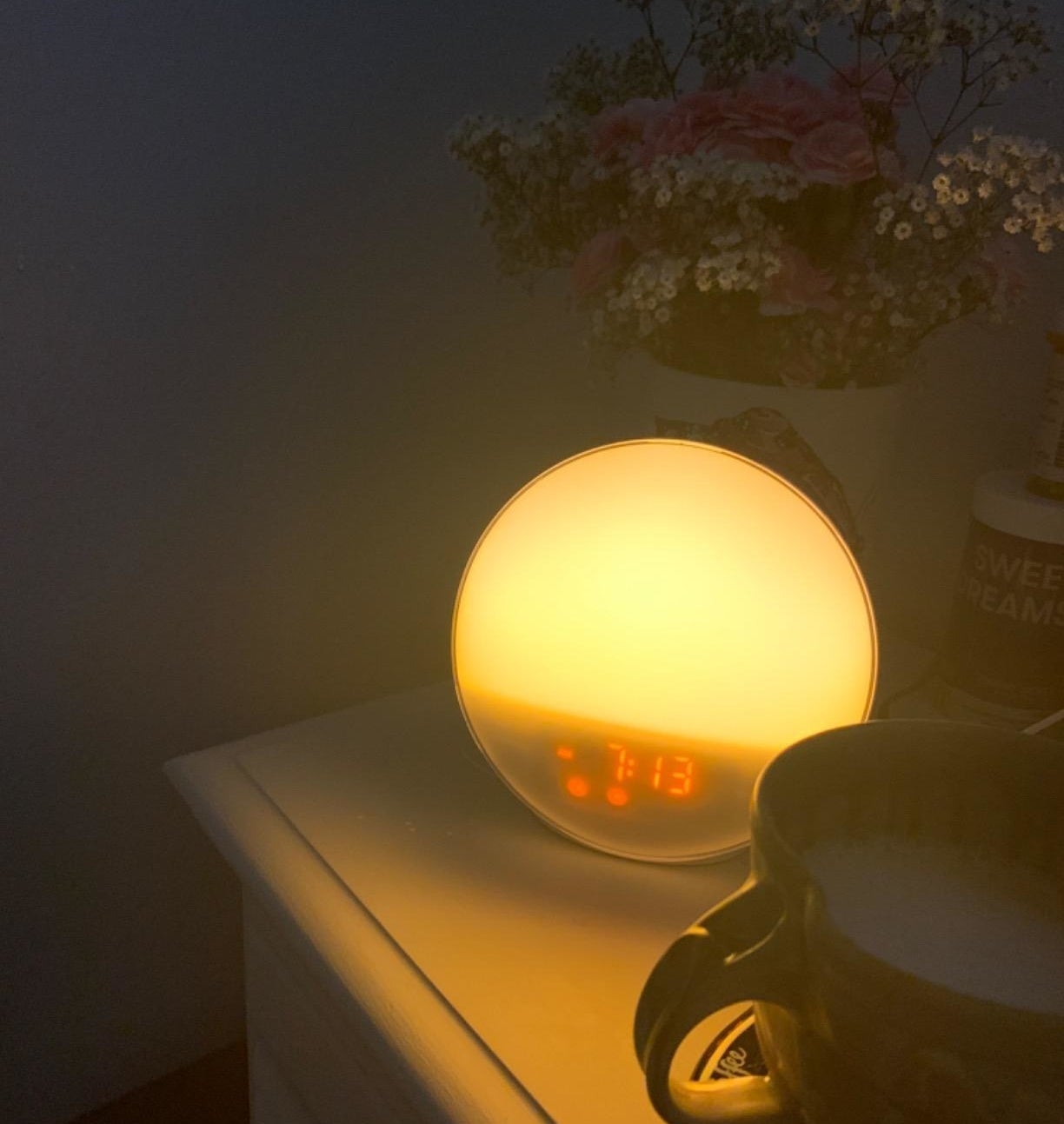 The lit up alarm clock on a nightstand