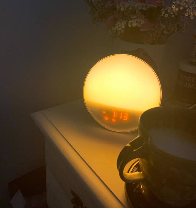 Reviewer's photo of the lit up alarm clock on a nightstand