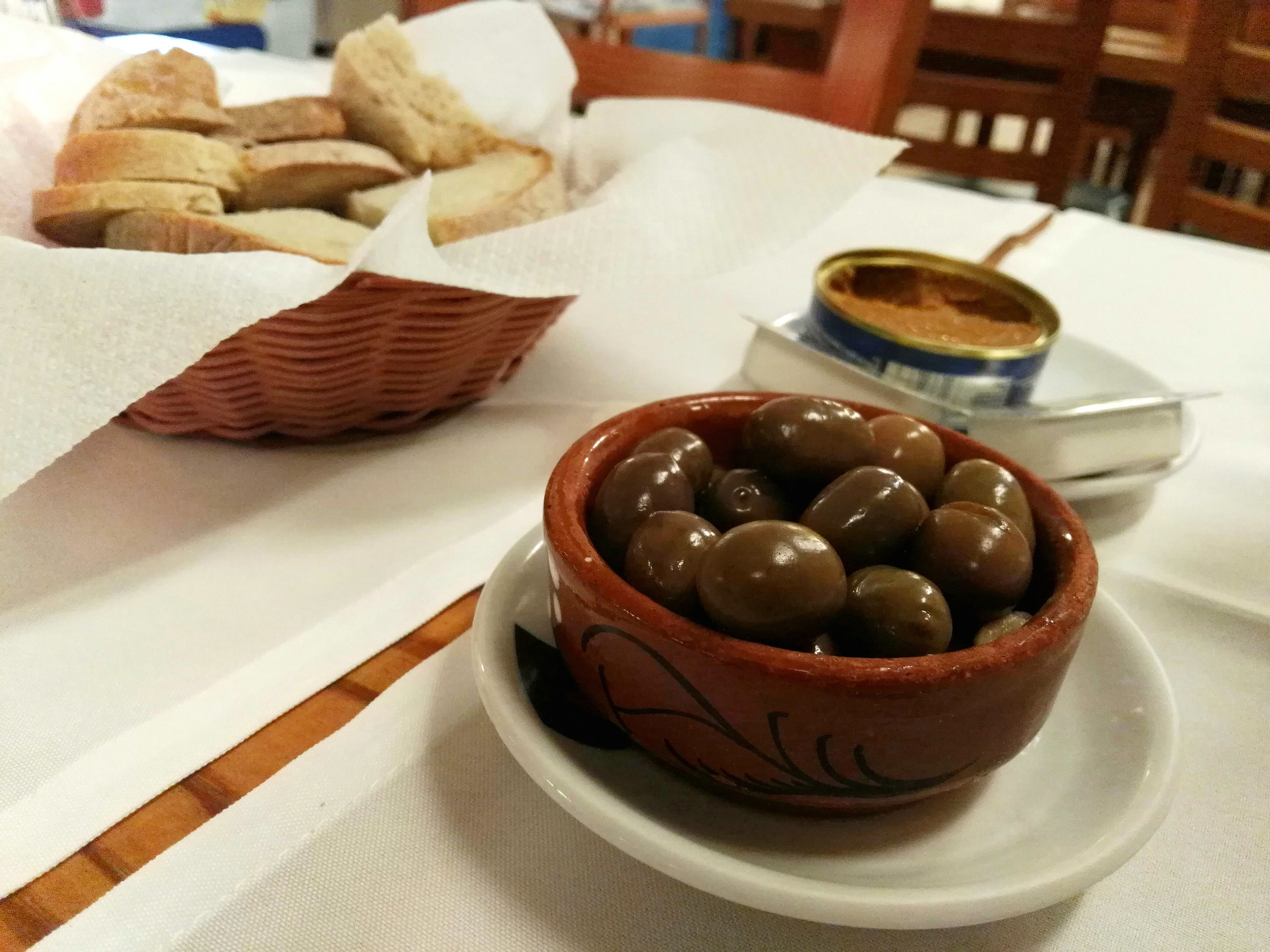 Olives and bread on a tabletop.