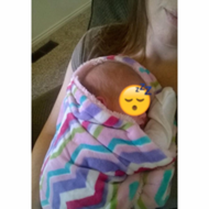 Reviewer's photo of the baby wrapped up in the cozy colorful blanket