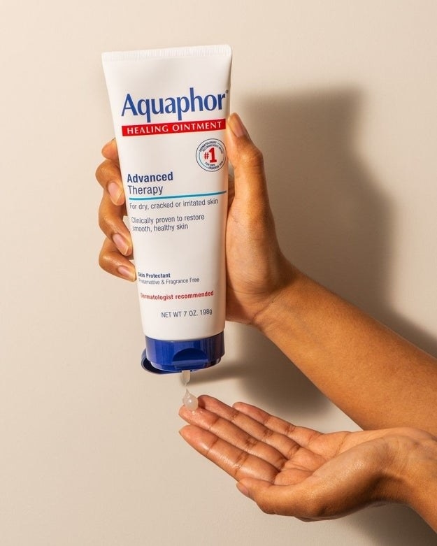 A person squeezing Aquaphor into their hand