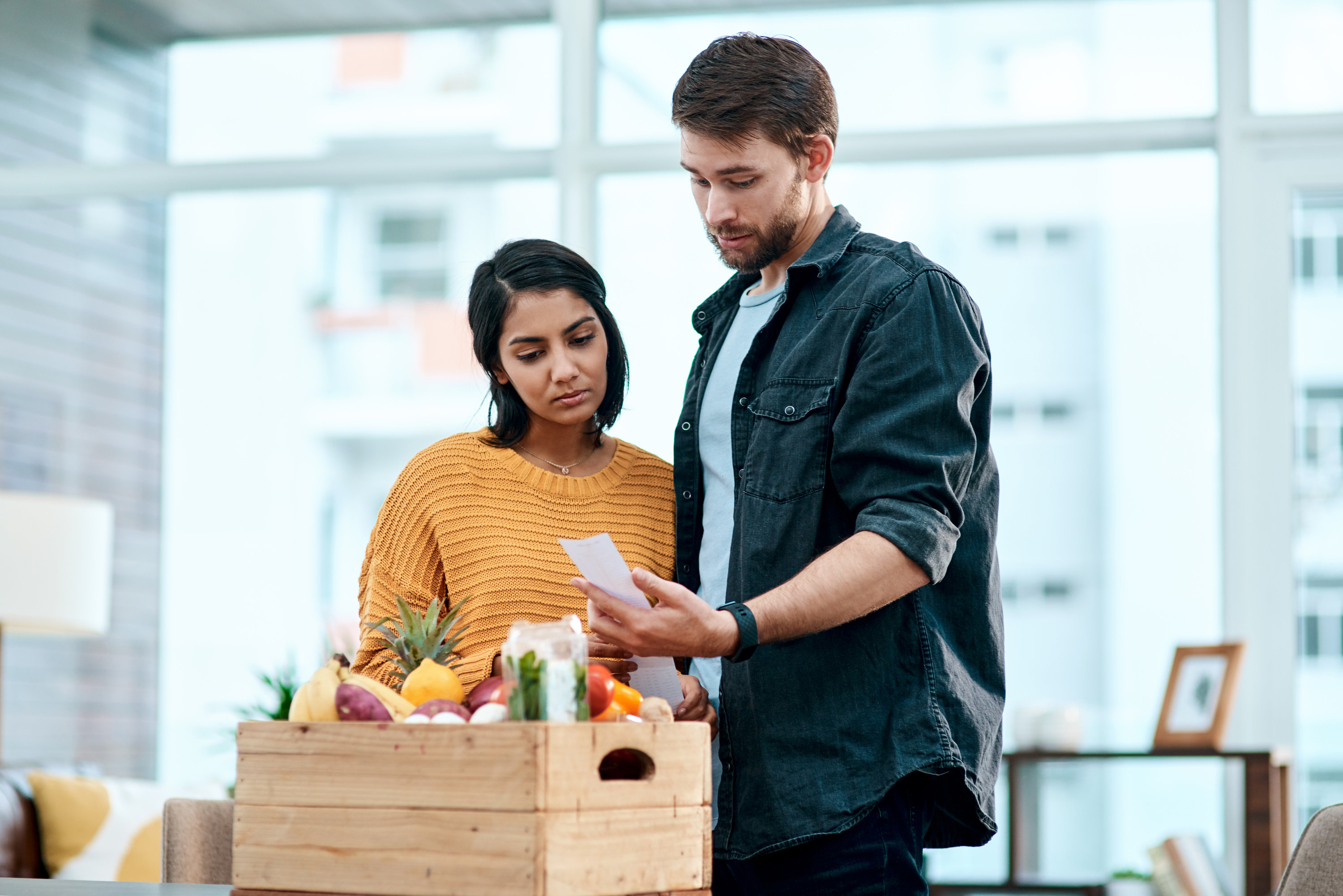 Couple looking surprised at their grocery receipt