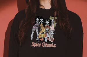a model in a black cropped hoodie with an illustration of the spice girls as ghouls on it