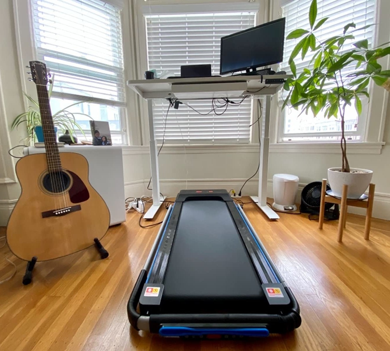 reviewer's folded treadmill under a desk, next to a guitar