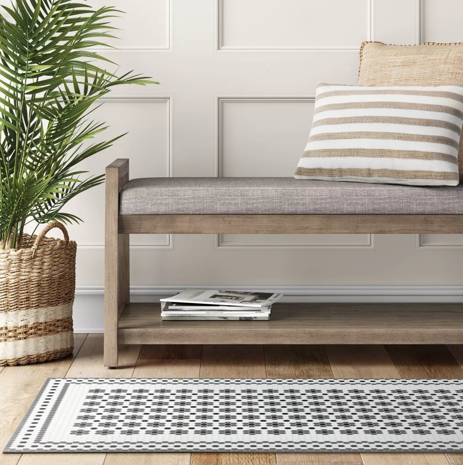 the gray and white tile mat on a wooden floor with a bench next to it with magazines on the bottom shelf and throw pillow on the bench top
