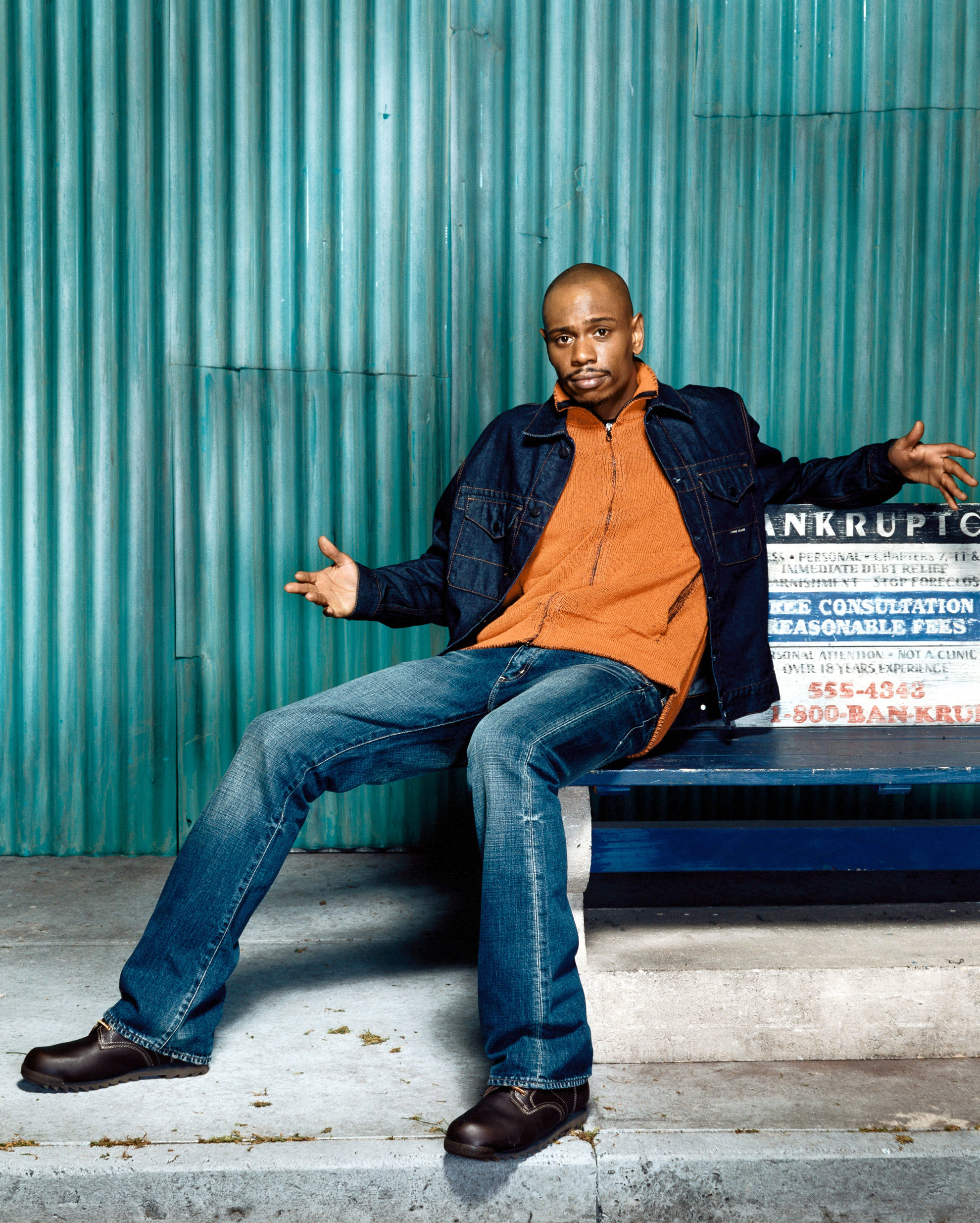 Dave Chappelle sitting on a bench in a promotional photograph