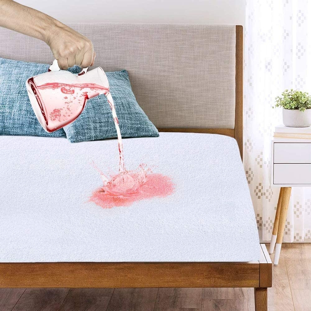 someone pouring a jug of liquid onto the mattress protector