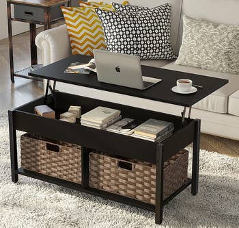 a black coffee table with the top lifted up to reveal an inner storage compartment