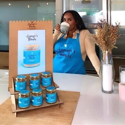 A black woman in an apron sips from a mug