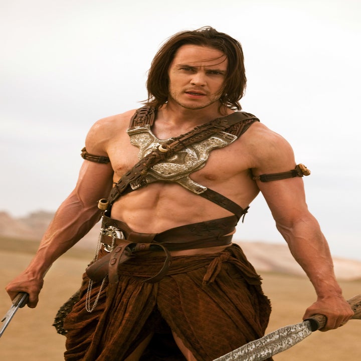 Taylor Kitsch as John Carter wearing a leather halter and holding two swords