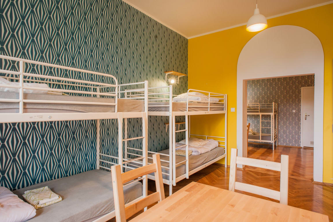 Set of bunkbeds in a well-decorated room with a graphic wallpaper design and small table with chairs